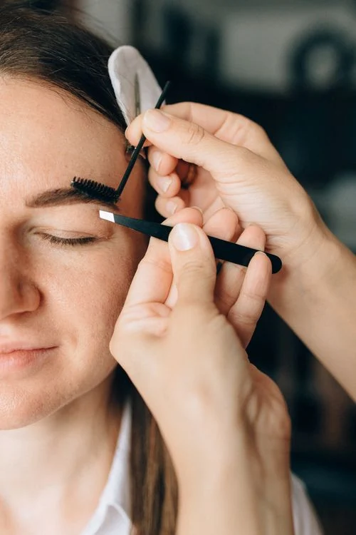 Close-up of eyebrow shaping with tweezers